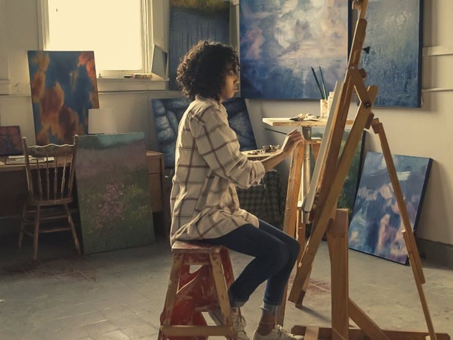 Artist painting at a wooden studio easel