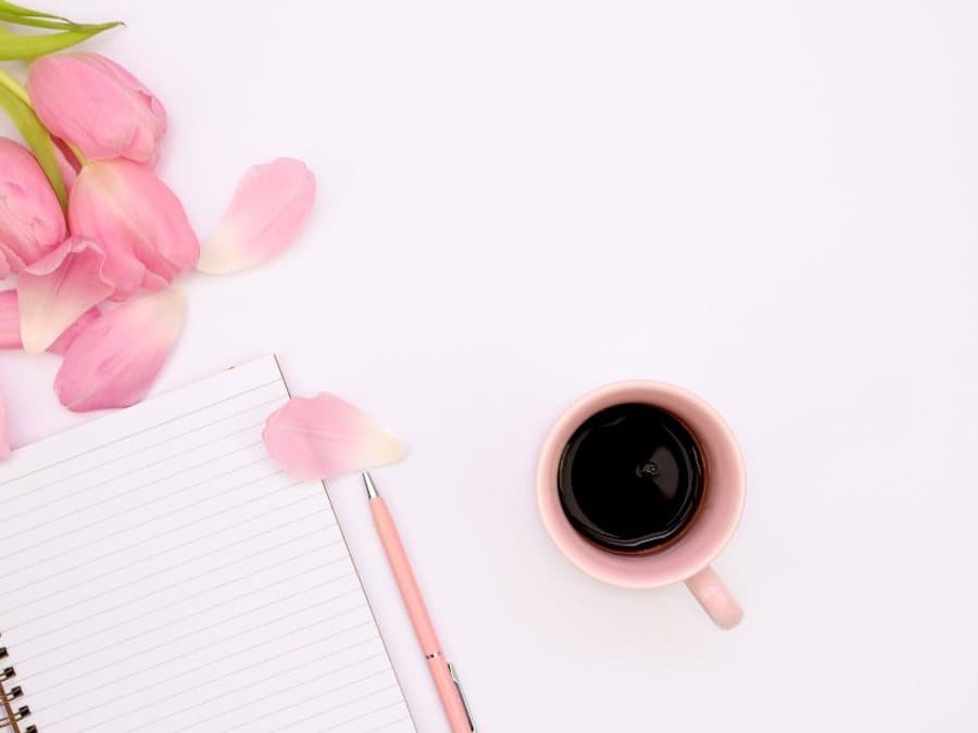 Lined notebook with a pen beside a cup of coffee