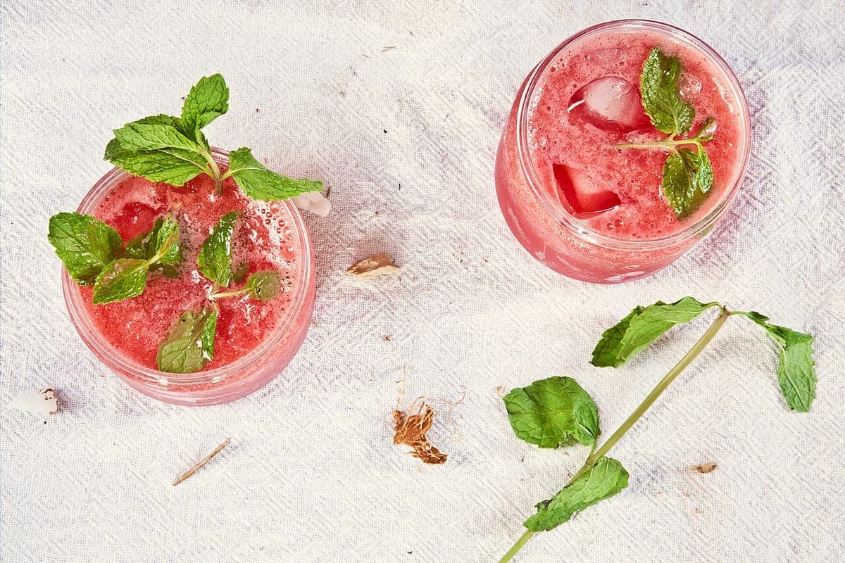 Two iced strawberry mojitos garnished with fresh mint