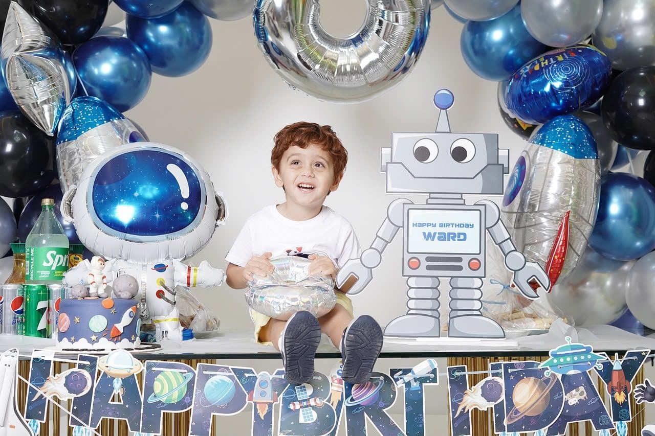 Boy laughing among space-themed birthday balloons