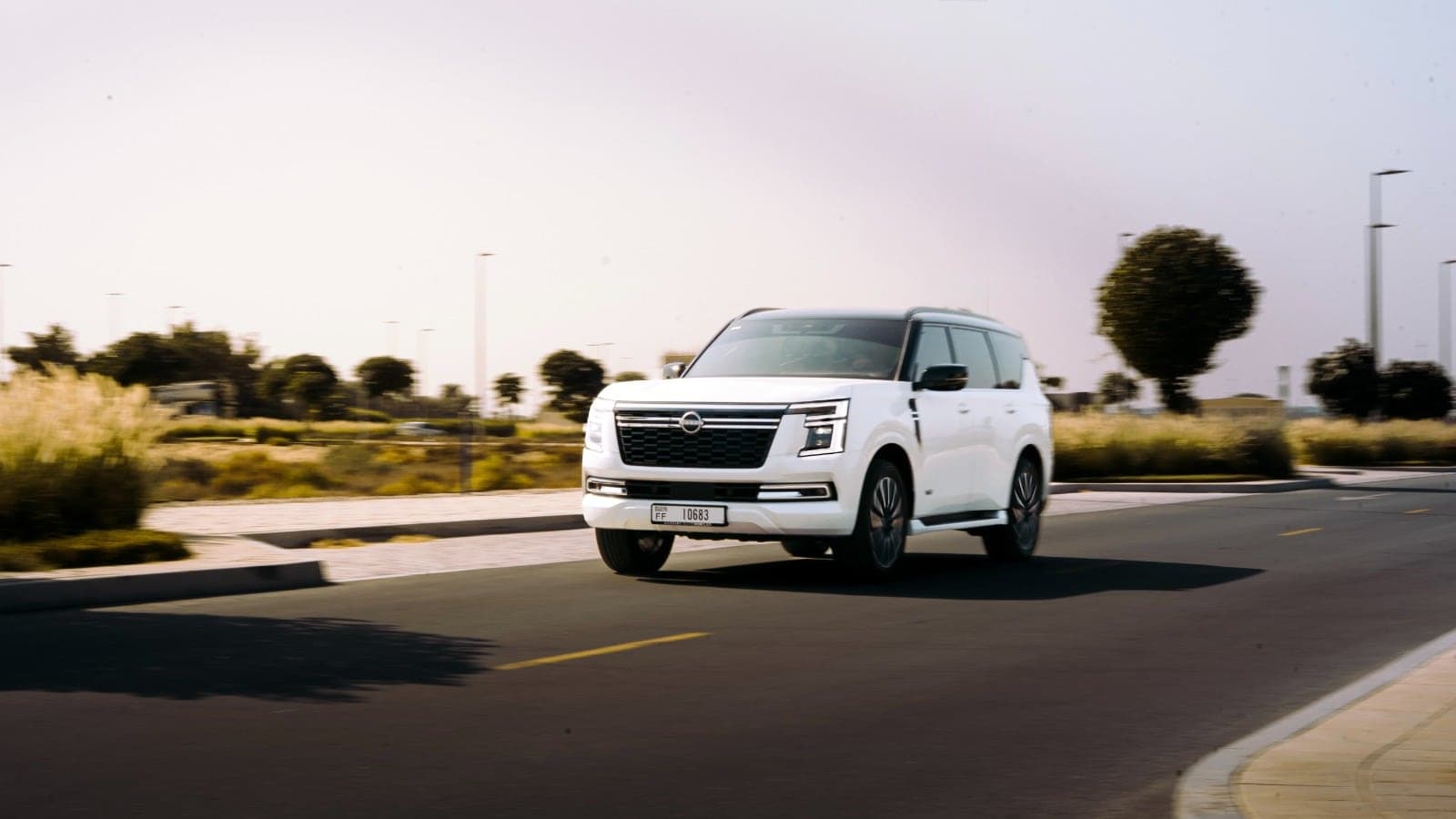 White SUV driving along a road past desert scrub