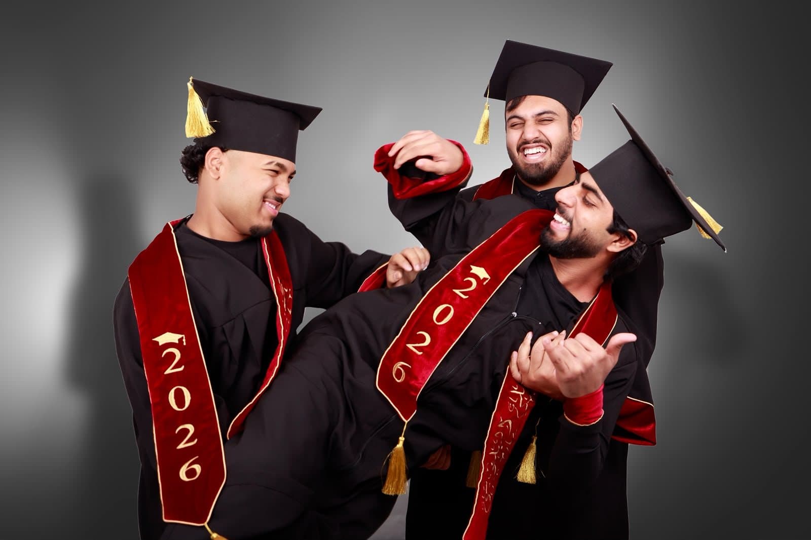 Three graduates in caps and gowns celebrating