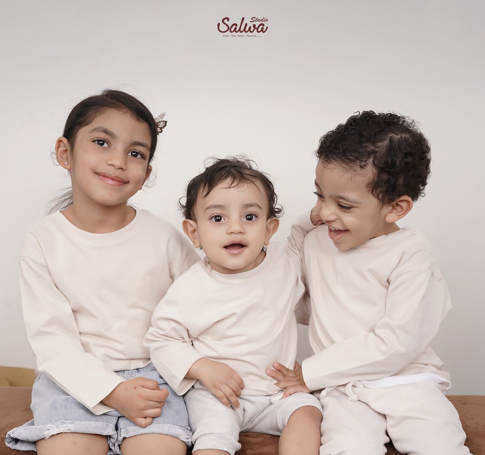 Three young siblings in matching cream tops
