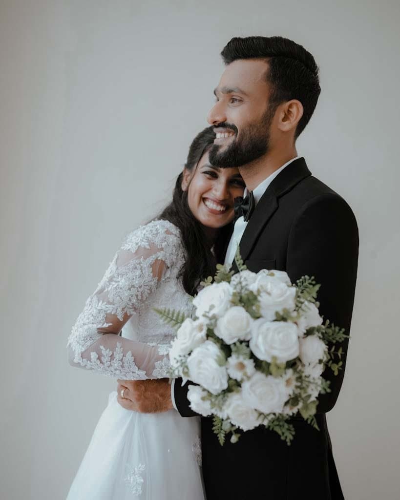 Smiling bride and groom holding a white rose bouquet
