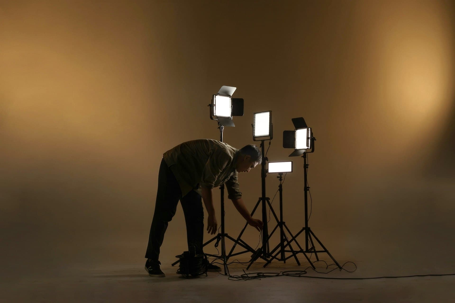 Photographer setting up studio lights against a warm backdrop